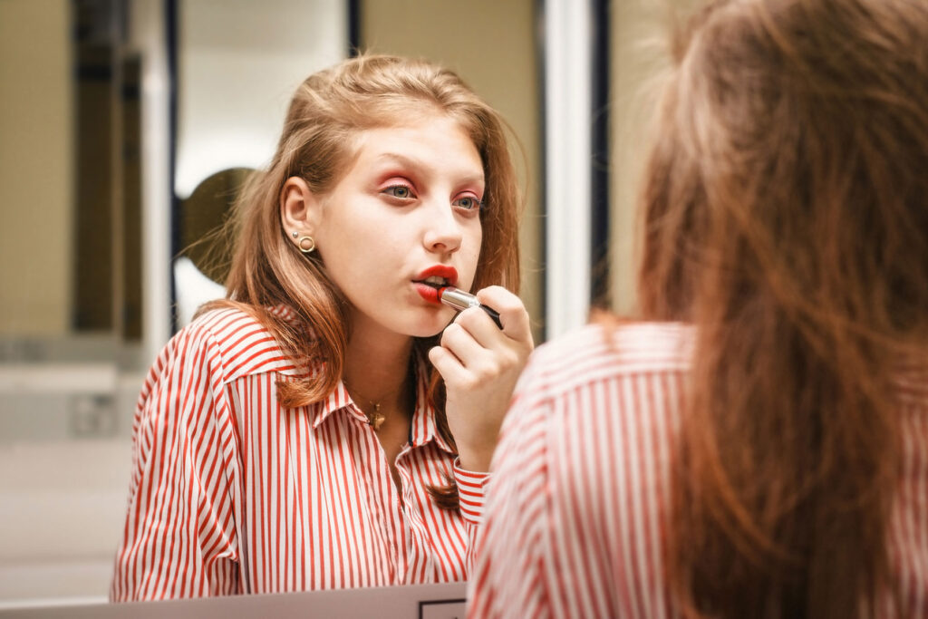 person putting on lipstick in mirror considering how are bipolar disorder and narcissim linked