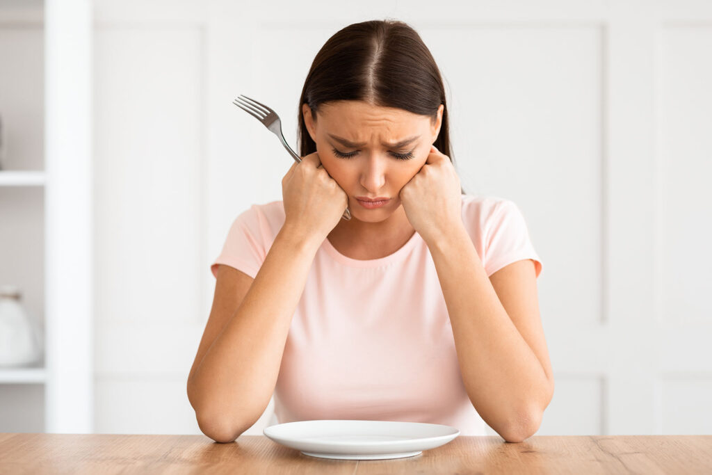 person frowning over empty plate while wondering how are depression and anorexia linked