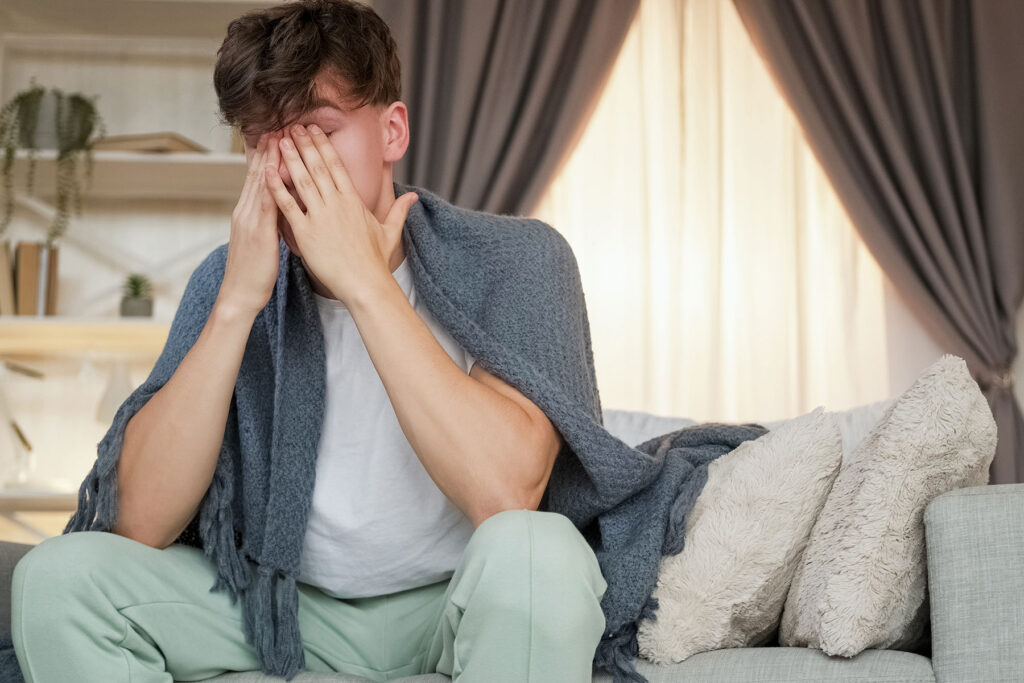 person sitting on edge of bed with hands on face while wondering what are the signs of mdma abuse