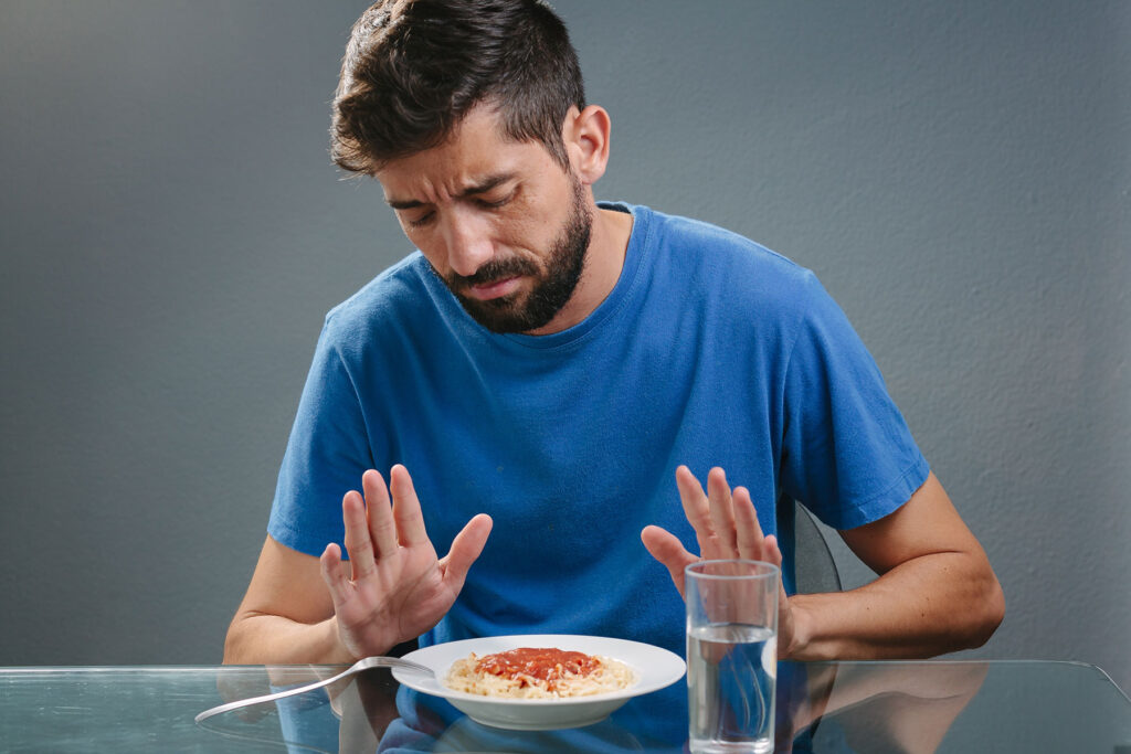 person refusing food at table to illustrate the question why does depression cause a loss of appetite