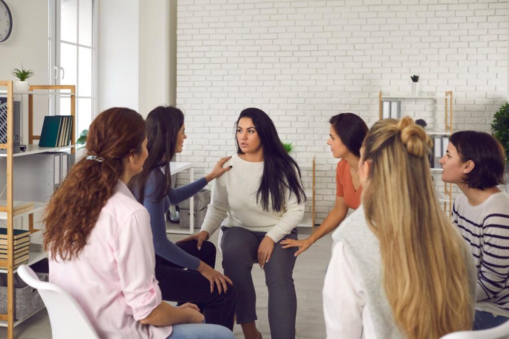 women comforting one another in group therapy while in rehab for women