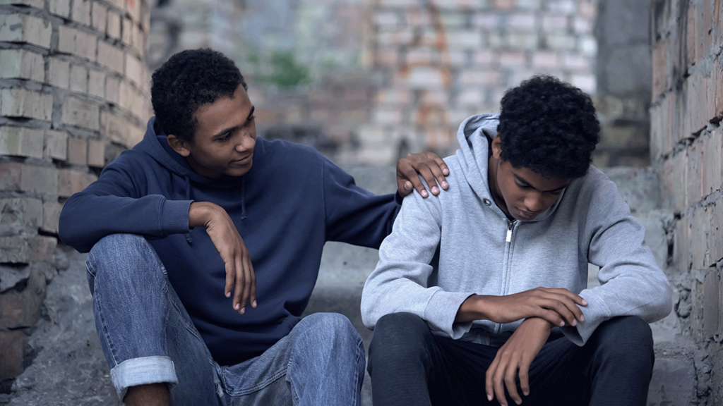 person sitting in alley with friend trying to offer support after learning how to help a loved one with depression