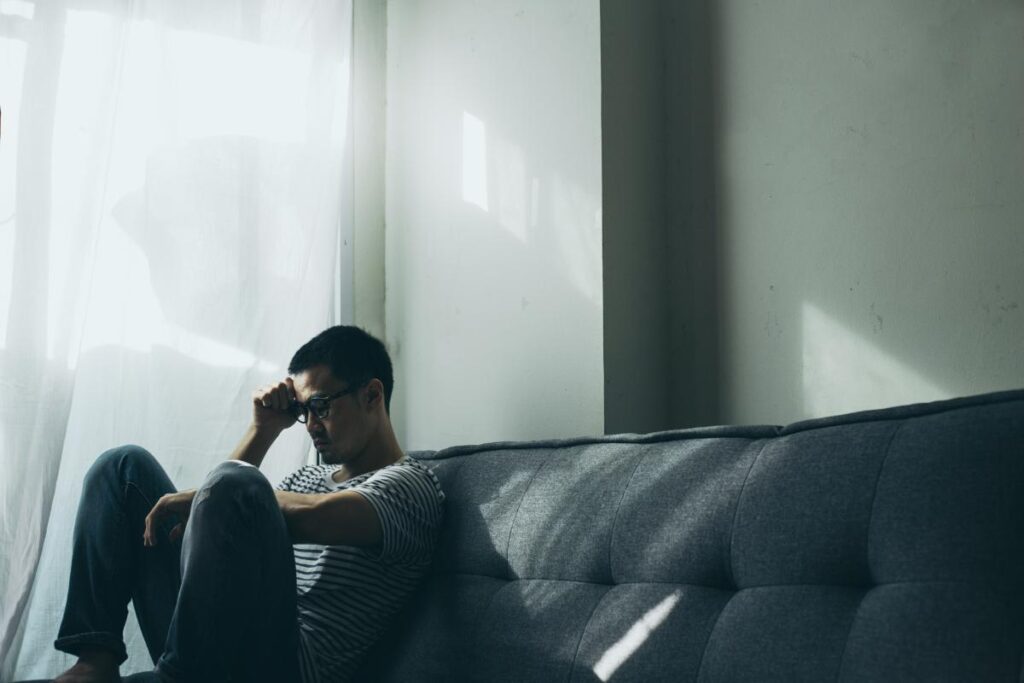 person sitting on couch in the dark wondering how long does cocaine stay in your system