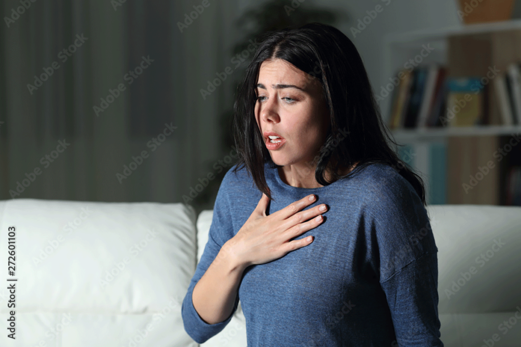 person holding hand over heart while struggling with panic as a trauma response
