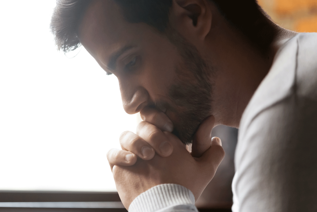 person sitting with hands folded contemplating alcohol and stress