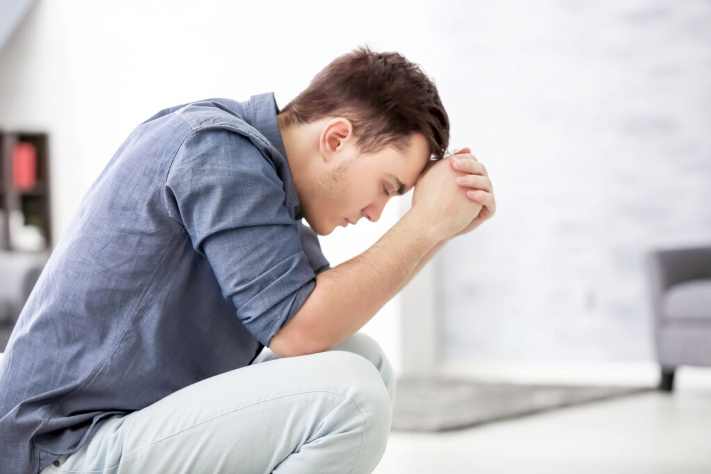 person sitting on couch hanging head while dealing with marijuana use and depression
