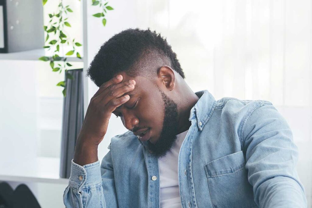 person hanging head while contemplating the link between ptsd and the brain