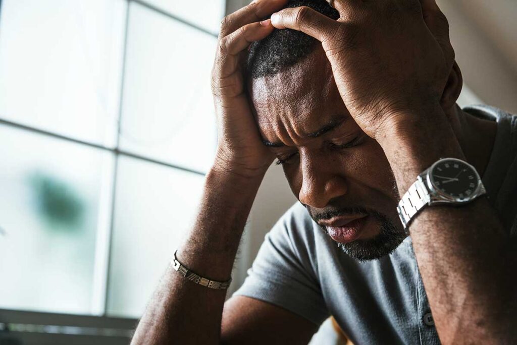 person hanging head in distress while dealing with problem drinking